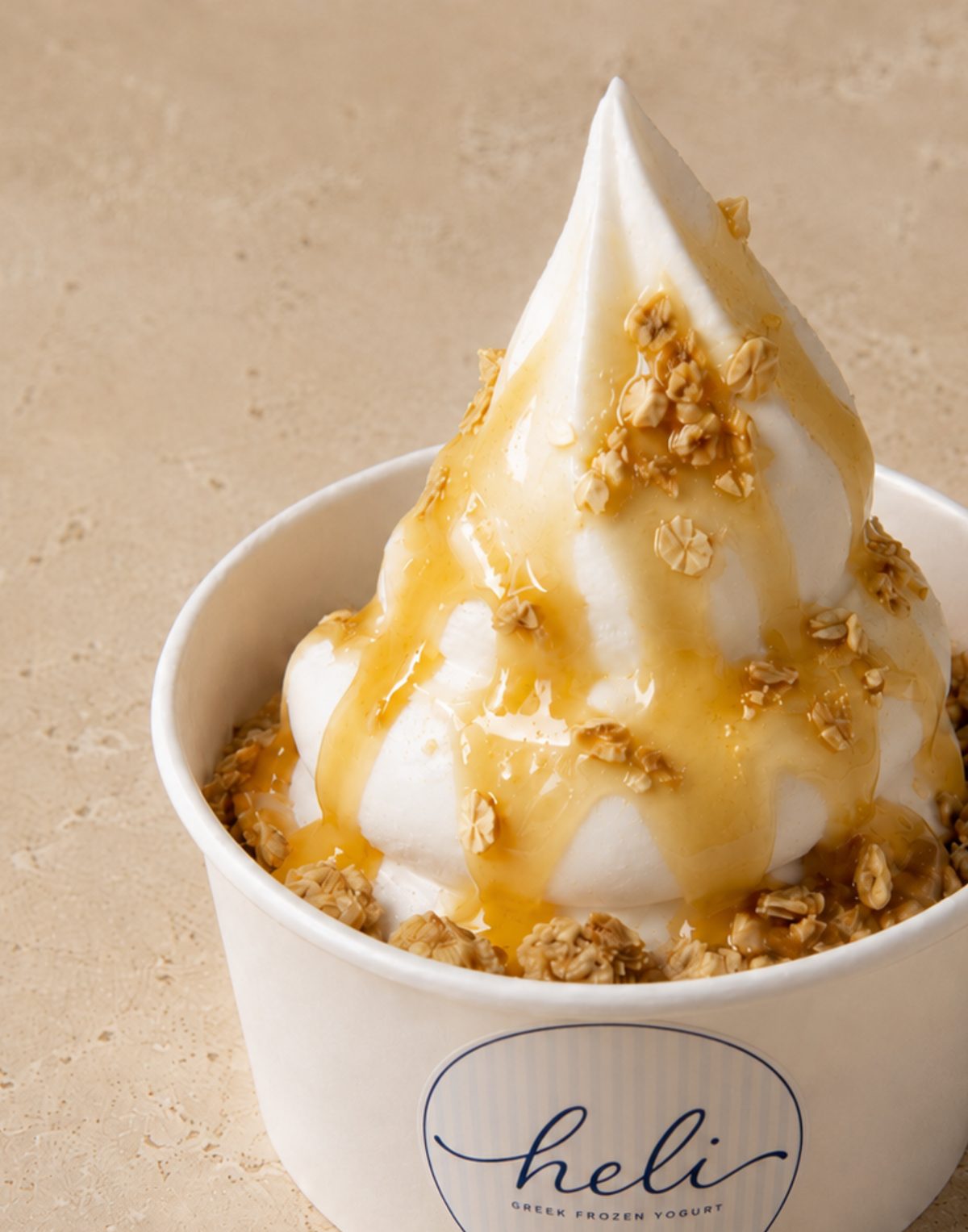 A finished Heli Greek frozen yogurt cup with honey and granola